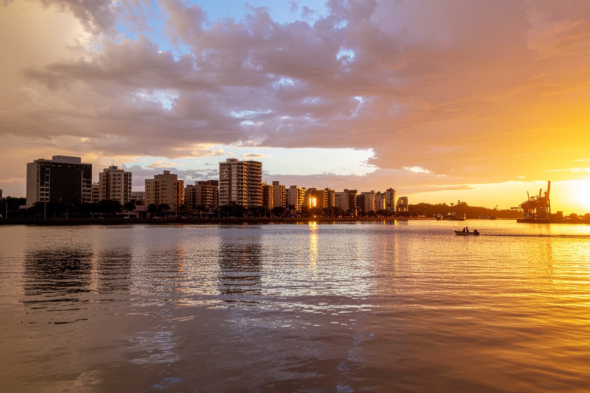 Vista do rio Itajaí-Açu ao entardecer, com prédios e porto ao fundo